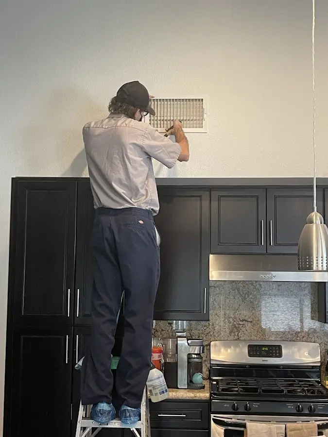 Technician inspecting an air vent during HVAC service in Lynnwood